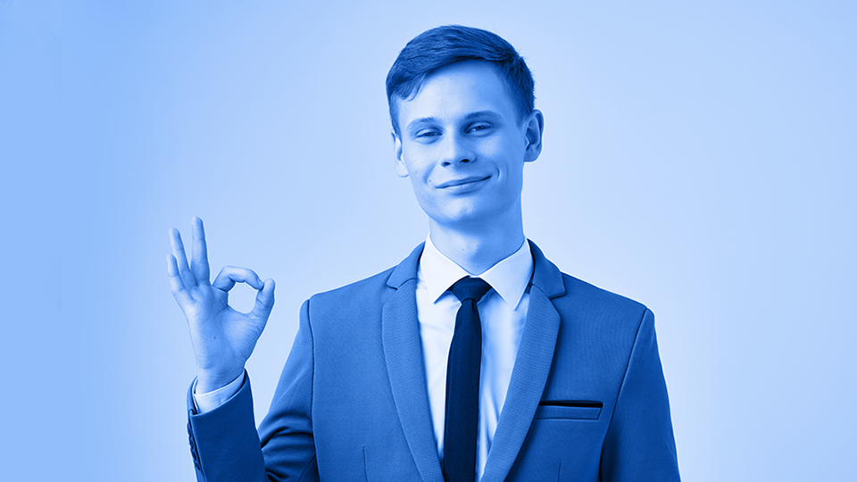 A white man in an office attire doing "OK" sign