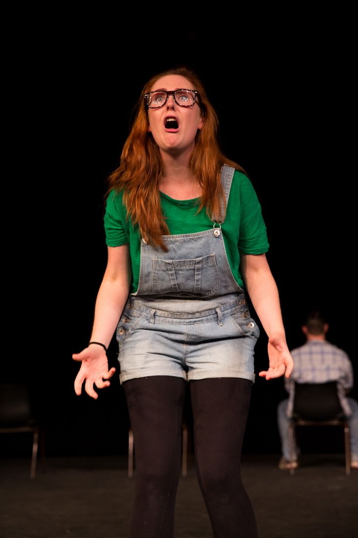 Female blonde wearing a glasses and green shirt with a jumper.