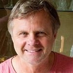 Wayne Mitchell - A middle aged man with a gold hair wearing a pink shirt