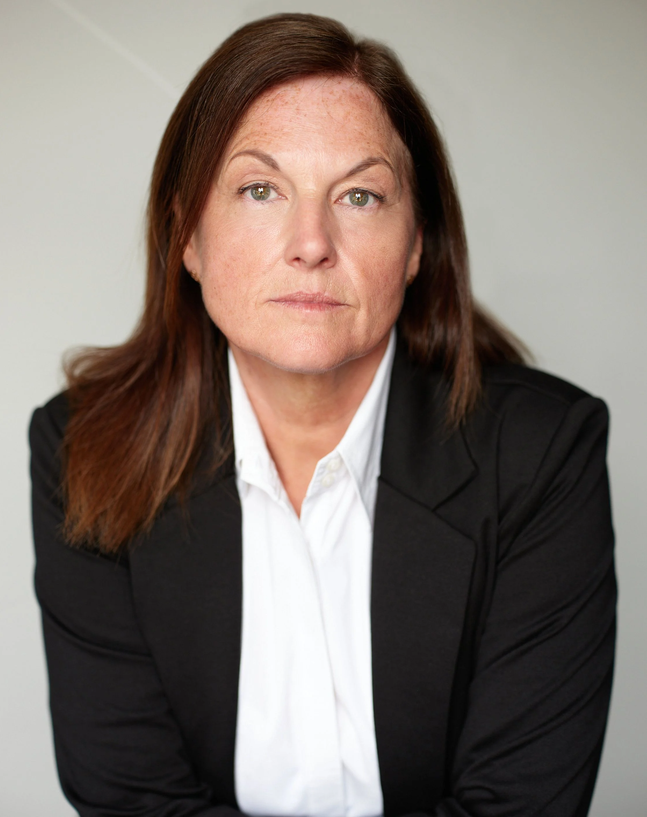 Michaela Short - A middle aged woman with a brown hair wearing a black coat and white polo