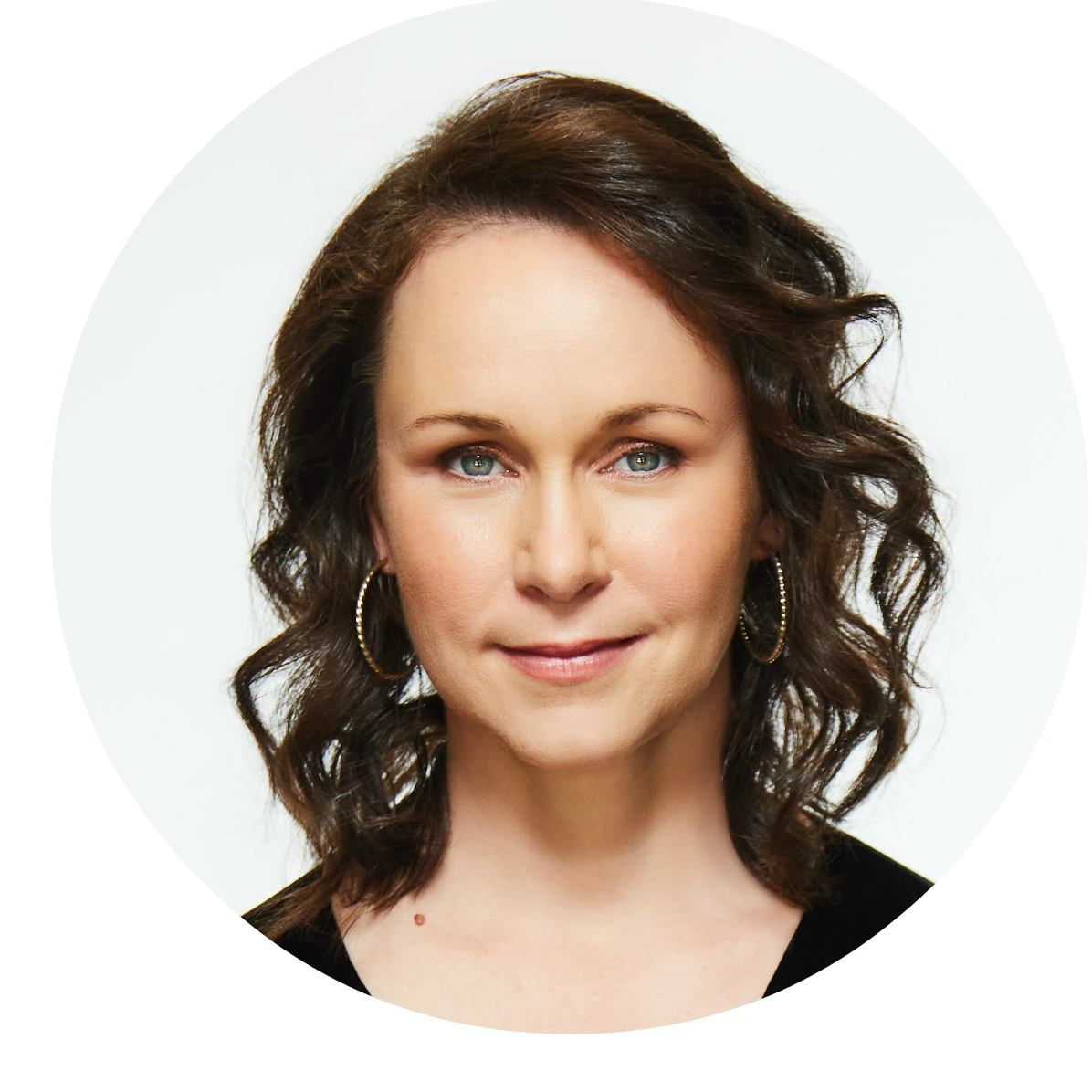 A dark curly haired woman with blue eyes and a huge circular earrings