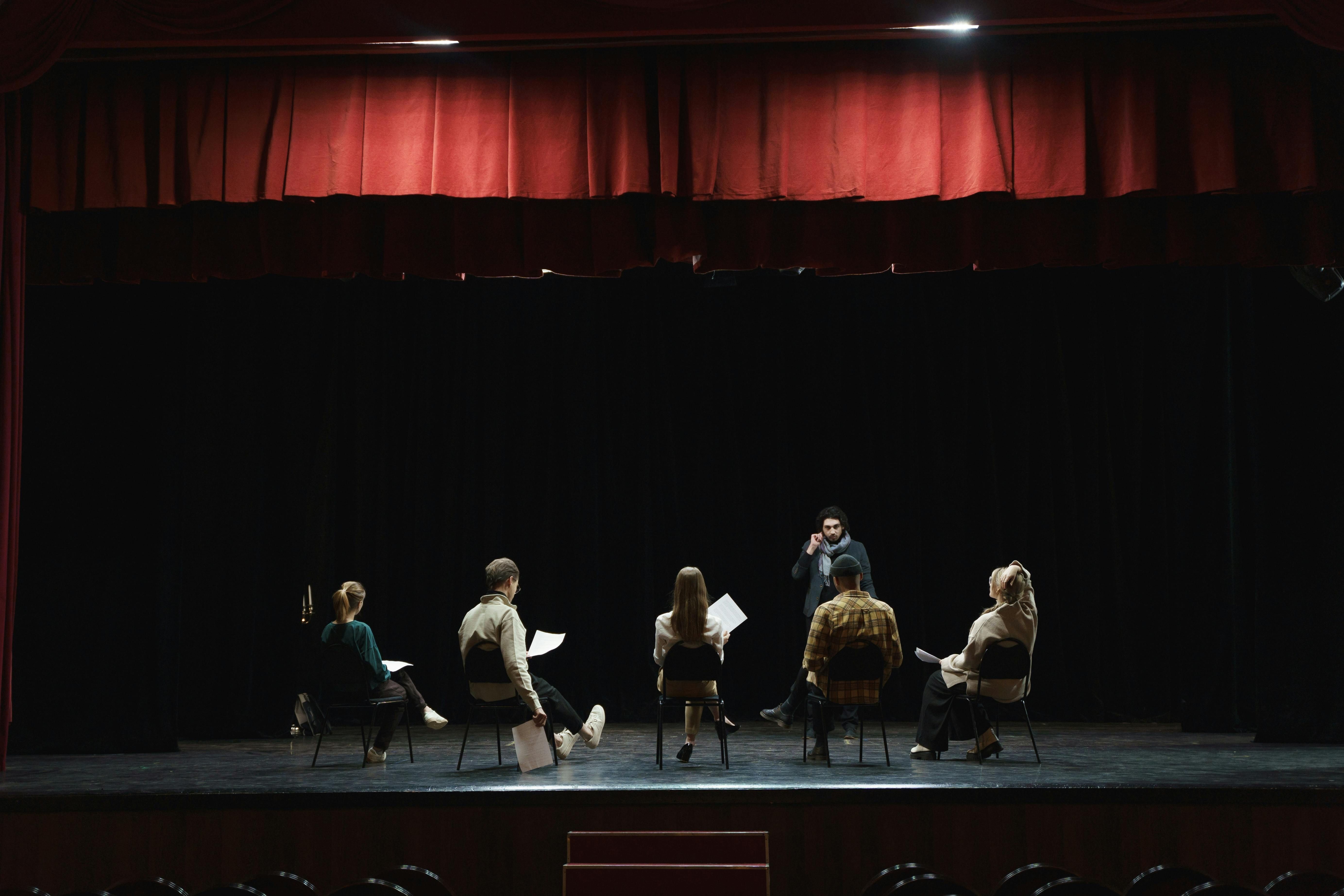 A mentor talking to his acting students on stage