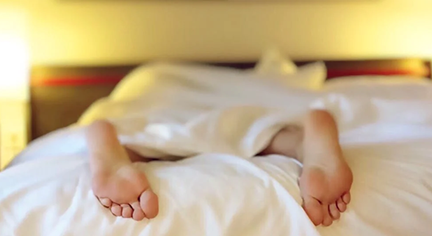 A person under the blanket that does not cover his/her feet