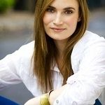 Eliza St John - A blonde woman, with a golden hair wearing a white blouse