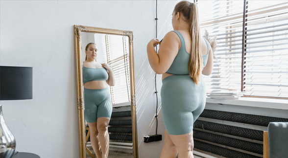 Plus size blonde female looking at herself in the mirror