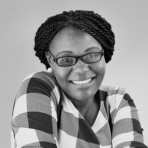 Chipo Basopo - A woman with braided hair wearing a glasses and a checkered blouse