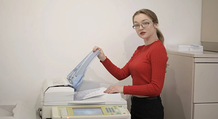 A woman trying to xerox a piece of paper
