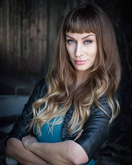 Nea Dune, A fierce woman with a blonde hair and a straight bangs wearing a leather jacket with blue shirt in the inside