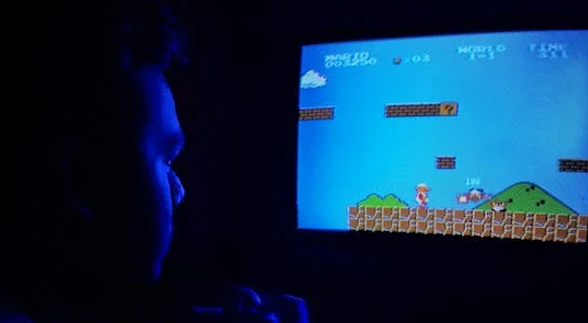 A male looking at a computer screen that plays mario bros