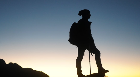 A silhouette of a Mountaineer at the top of a hill
