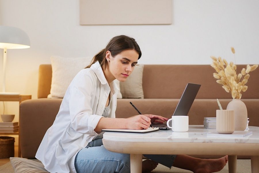 A woman sitting cross-legged on the floor, using a laptop.