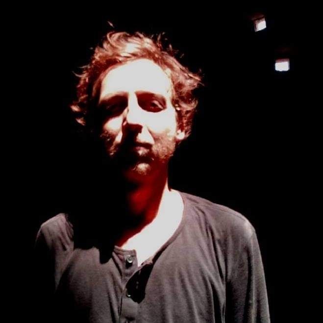 Danetto - bearded guy with brown hair and a black shirt with spotlight 