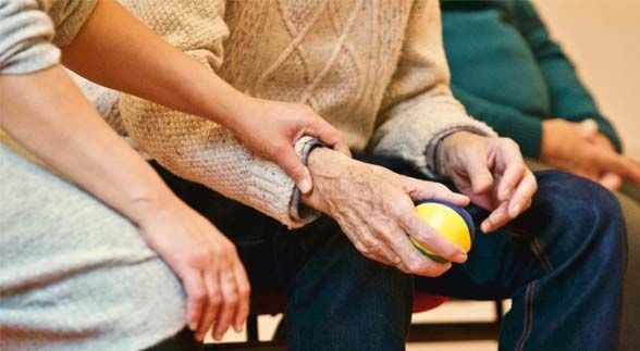 A man holding a lemon while another woman is holding his wrist in a group meeting