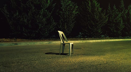 A monoblock chair in the middle of the road 