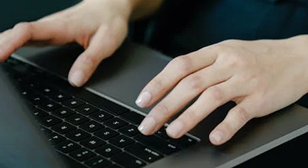 A hand typing in a laptop keyboard