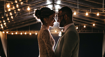 A newly wed couple staring in love with each other with full of lights in the background