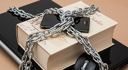 A laptop, mouse, cellphone and a book tied and locked up together with a chain