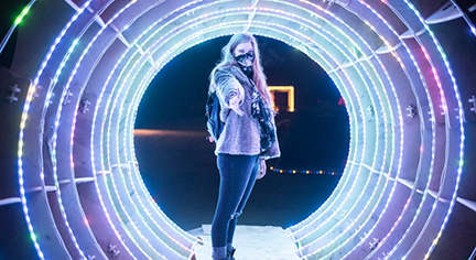 A woman standing infront of a tunnel of lights