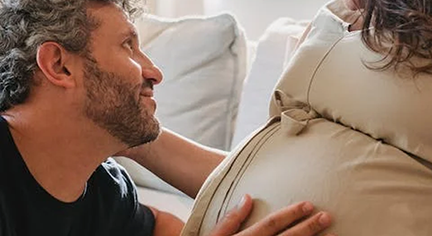 A husband touching her wife's pregnant belly
