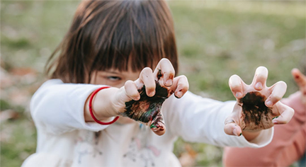 A short haired kid with a dirt in her hands