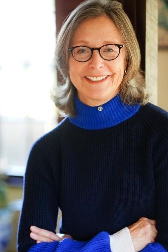 Donna Morong - A middle aged blonde woman wearing a glasses and a blue turtle neck 