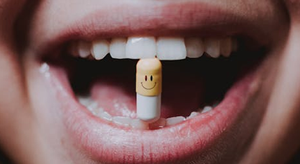 Mouth biting a pill with a happy face on it