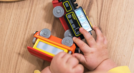 A hands of a baby holding a toy train