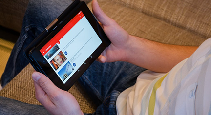 A guy holding his table while taking time to pick a video to watch