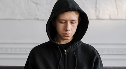 A man in a black hoodie staring down to the floor