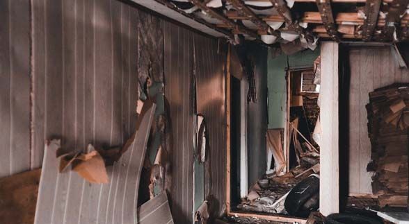 An apartment that has a shattered ceiling and wall