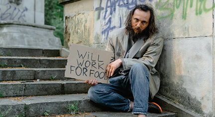 A beggar sitting on the streets holding a sign board