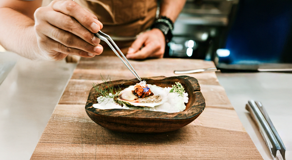 A family holding each other hands and sitting in a dining table with a lot of food