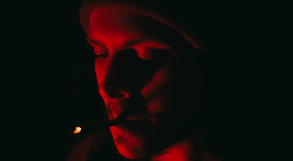 A male puffing his cigarette with a red lighting reflection