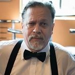 Jimi Elwell, An elegant man wearing a white shirt and black bow tie, sitting at a table.