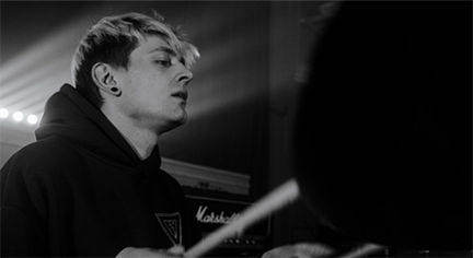 A black and white image of a guy playing the drums