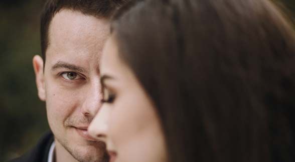 Half face guy shown in the image while the other half is covered by a woman infornt of him