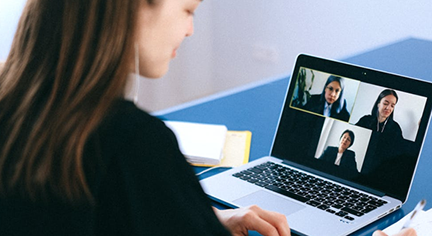 A woman infront of a laptop doing zoom meeting
