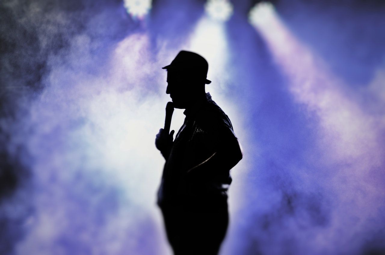A silhouette image of singer on stage with lightings on him