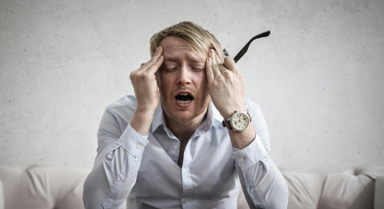 A man with blonde hair sitting on a couch that seems to be confused and problematic