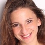 Xenia Bovitori - A brown haired lady wearing a big smile