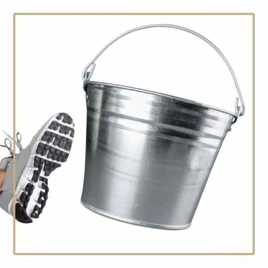 a white training shoe kicking an aluminium bucket on a white background