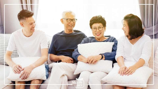 Asian family on couch holding pillows mum dad daughter son
