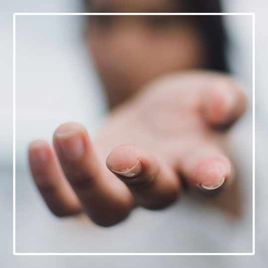 An out-stretched hand with palm turned up on grey background