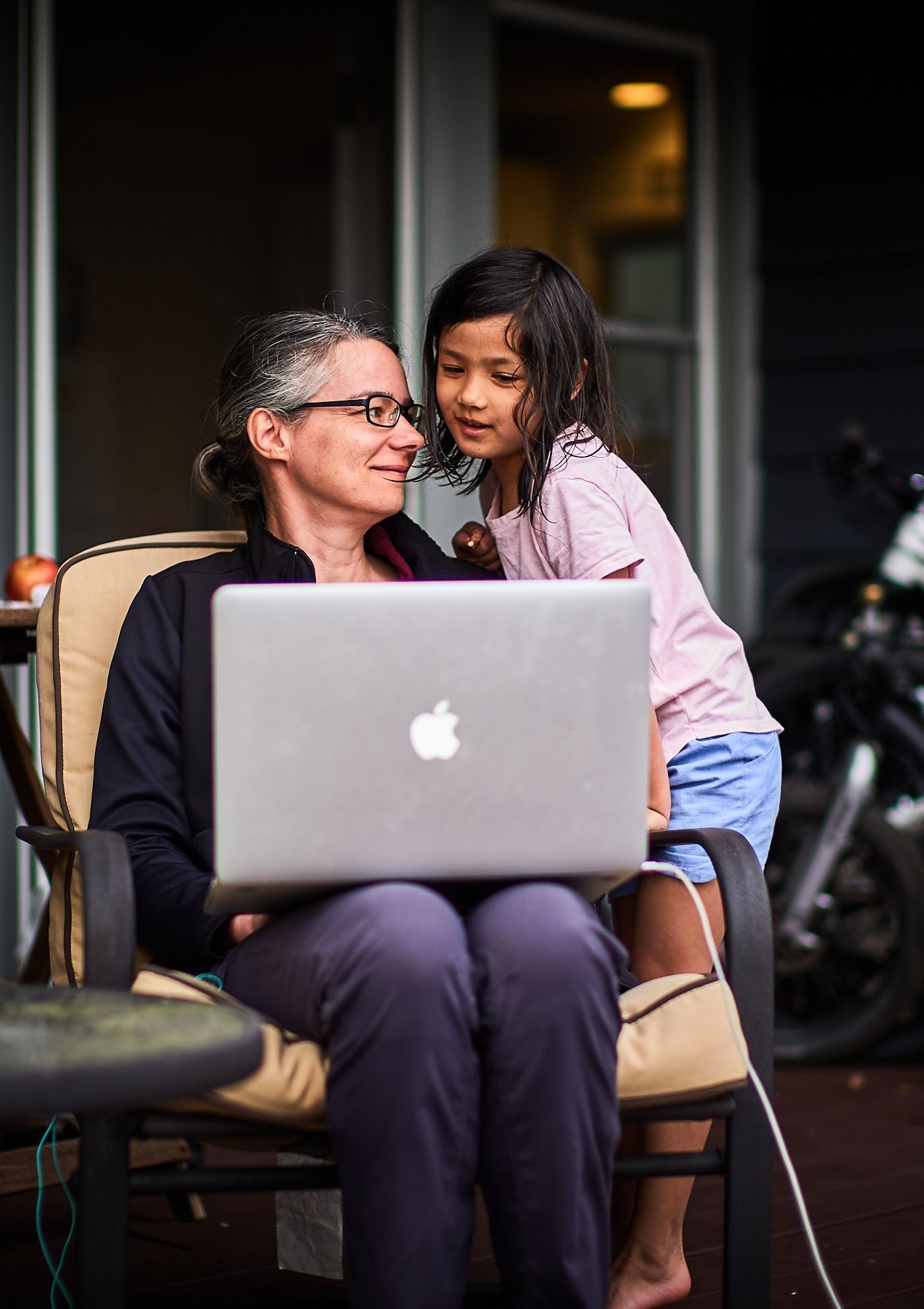 Carys stands smiling on a snowy mountainside wearing a pink fleece jacket, with snow-capped peaks and blue sky behind her.