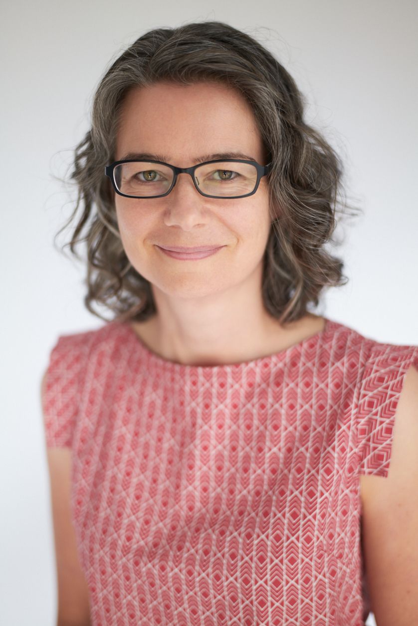 Jen Lumanlan, parenting coach and host of Your Parenting Mojo podcast, smiling at camera wearing glasses and pink patterned top