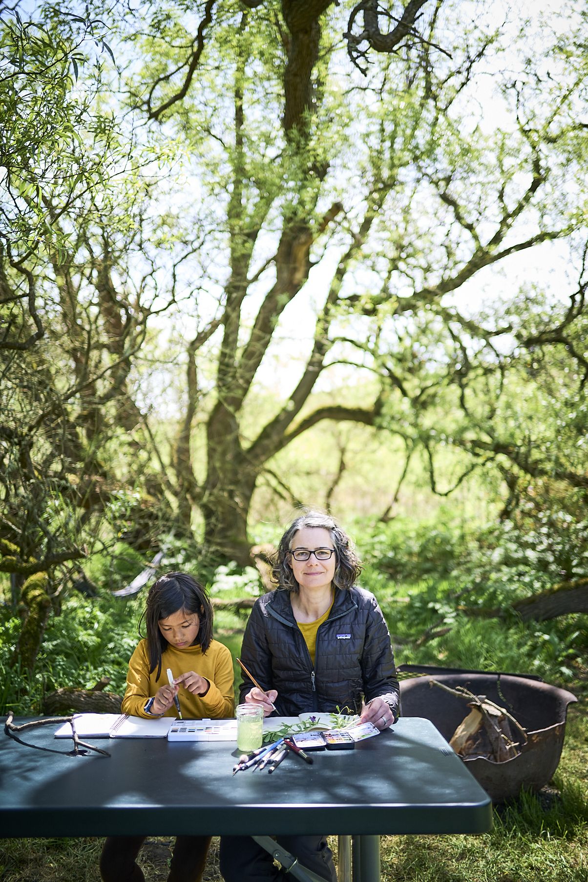en Lumanlan calmly engaged in a creative activity with her daughter outdoors, showing peaceful parent-child connection