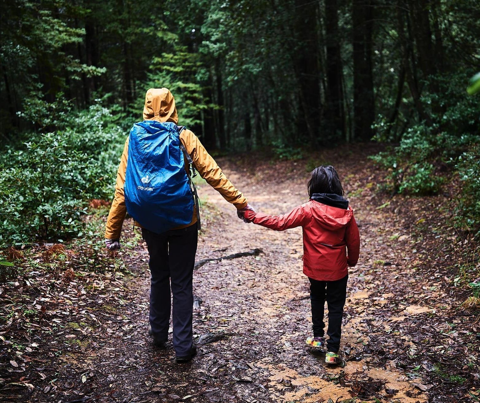 Child's legs in red polka dot pajamas stretched up behind a gray couch in a warm, book-filled living room