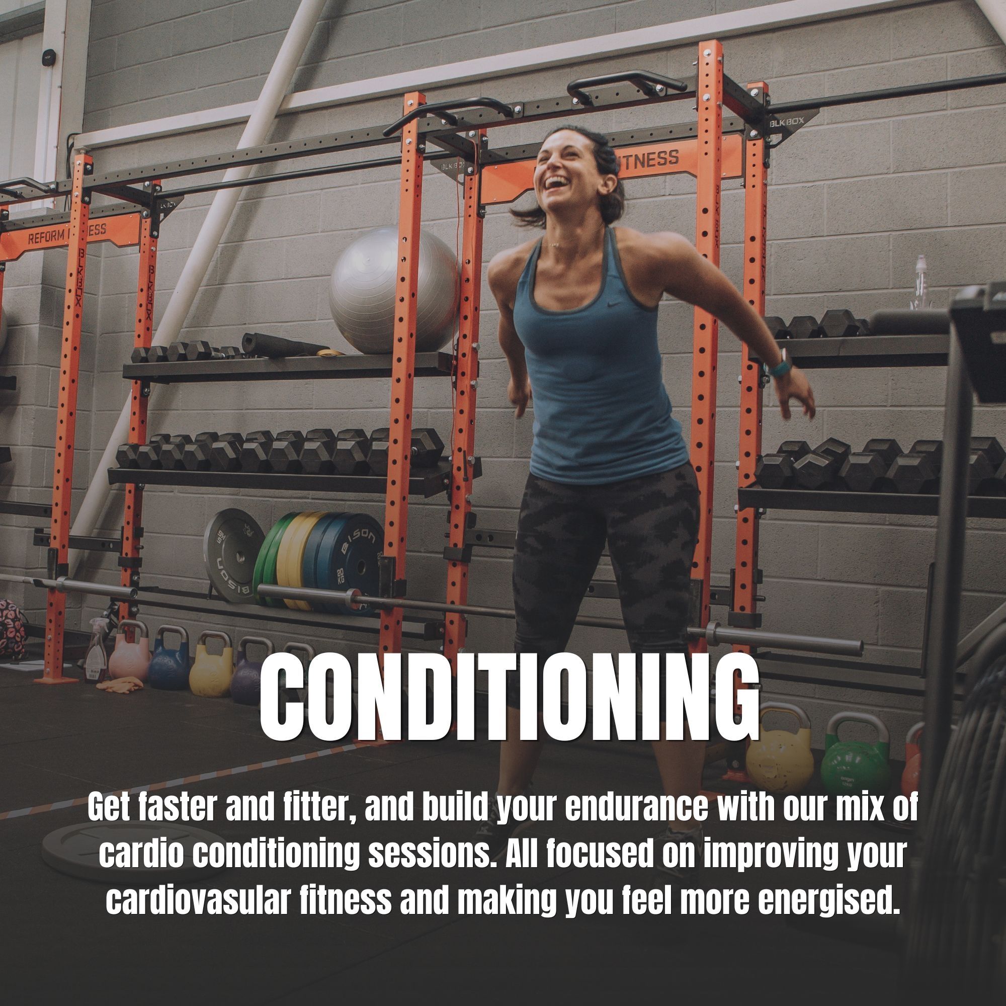A woman in the gym jumping and smiling.