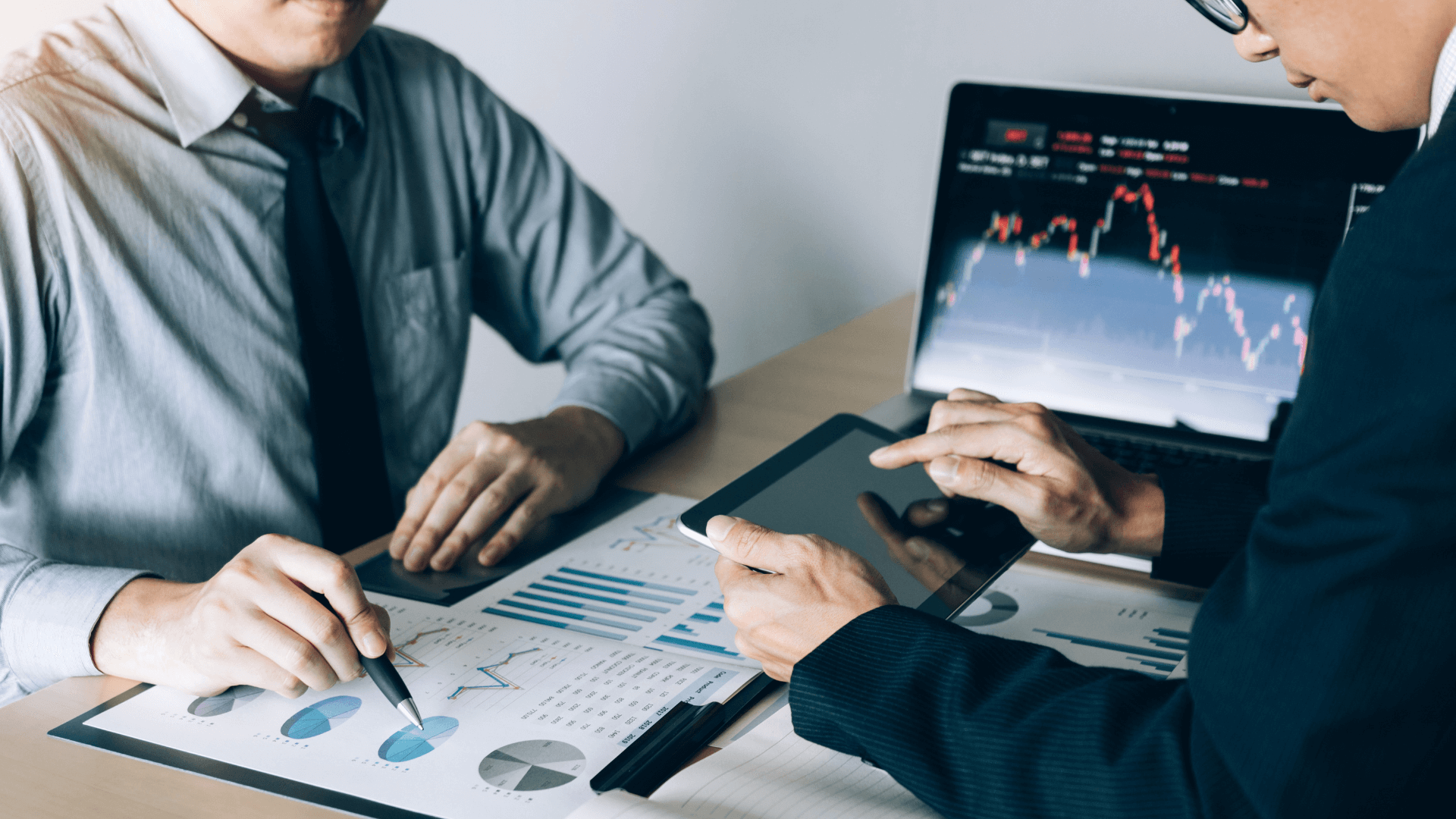 An image depicting a strategic discussion between an investor and a financial advisor, with charts and property market reports on the table.