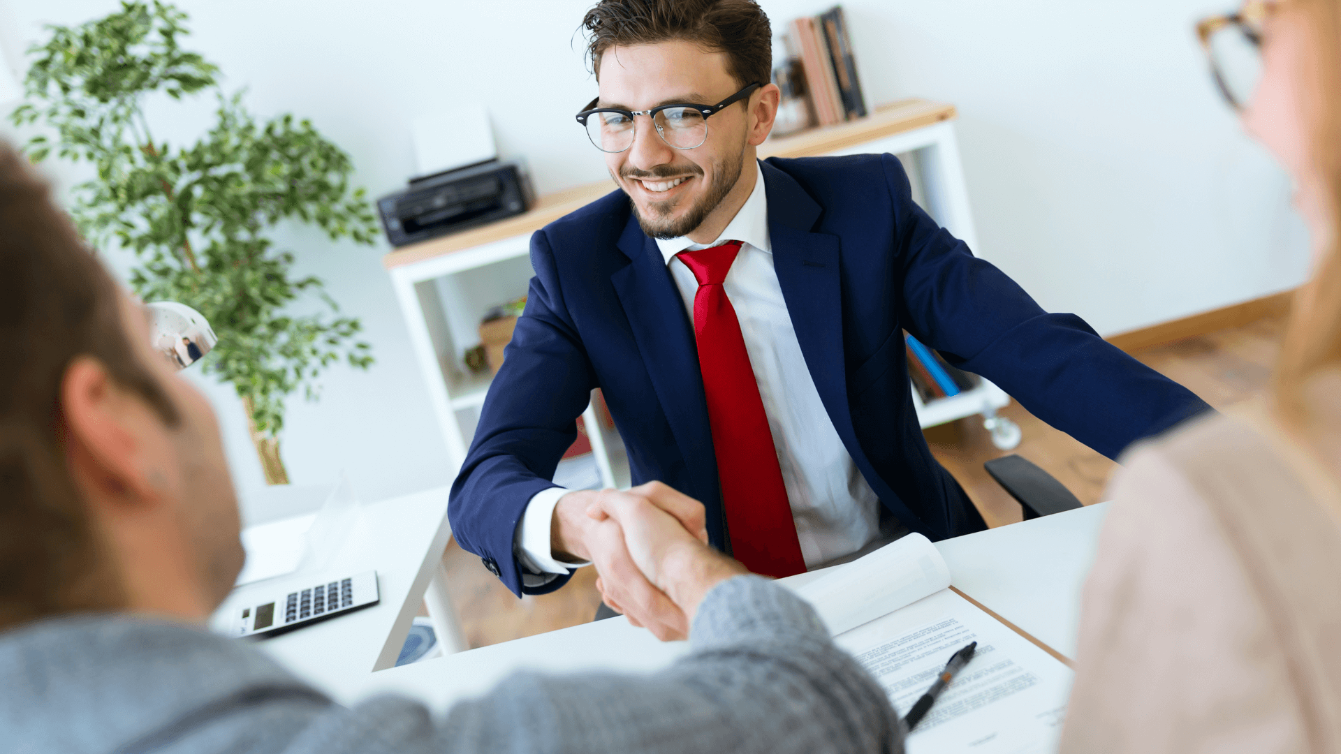 A tense but professional negotiation scene, possibly showing hands shaking or people discussing terms across a table with contract papers.